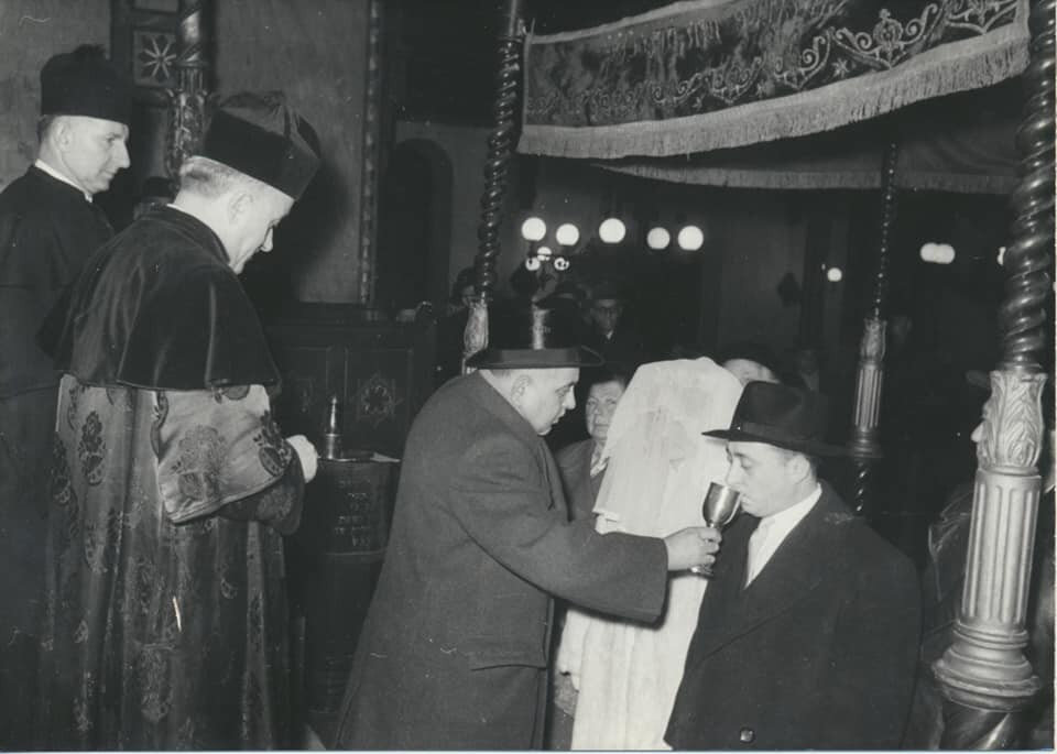 Esküvő a Dohány utcai zsinagógában / Fisch Henrik rabbi mellett Lóránd Márton kántor áll, poharat Zoldán Sándor tartja a vőlegénynek. Budapest Fekete-fehér fotó (1945 után) / Forrás: Magyar Zsidó Múzeum és Levéltár